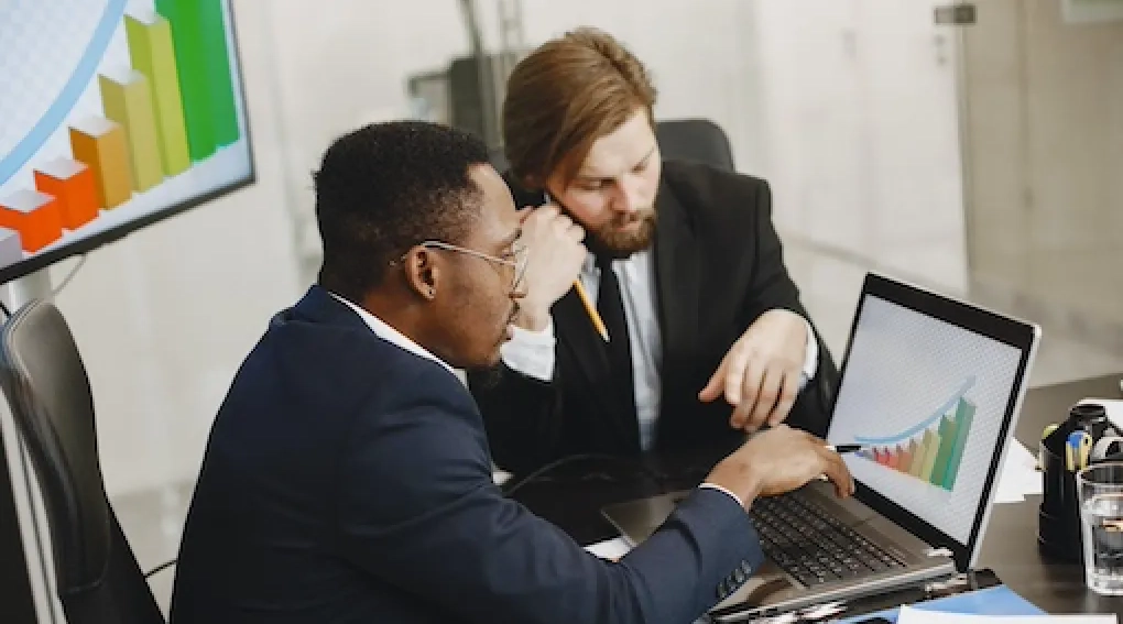 Two men discussing data on a laptop