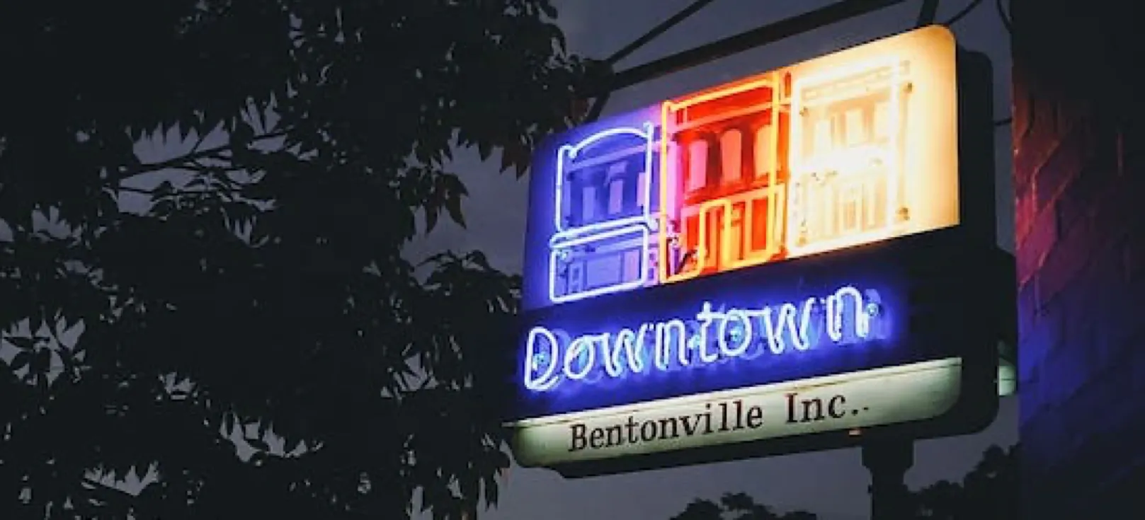 Neon sign reading ‘Downtown Bentonville Inc.’ at night