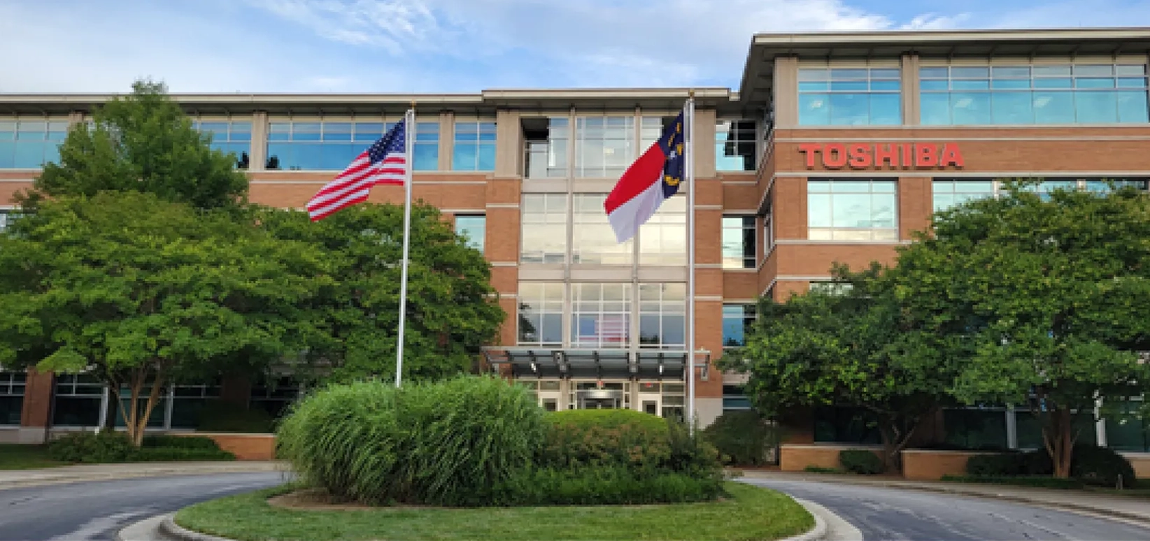 Office building with flags and greenery in front