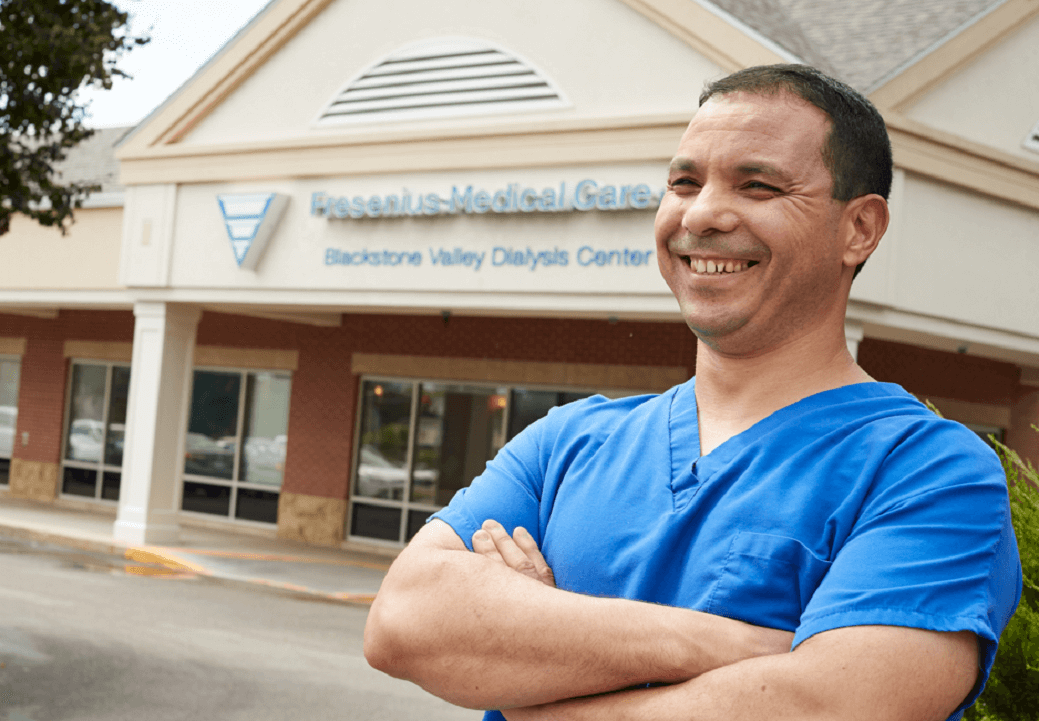 Nurse in blue scrubs standing in front of a clinic