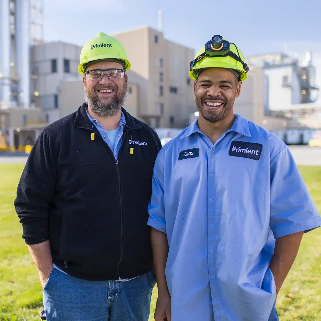 Two Primient people wearing hard hats smiling