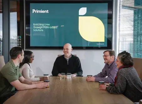 employees sitting at a conference table listening to a presentation 
