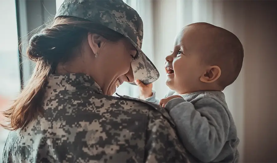 Woman in military uniform holds a smiling baby
