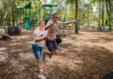 a woman pushing a child on a swing
