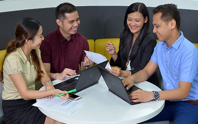 a group of people sitting on a couch looking at laptops