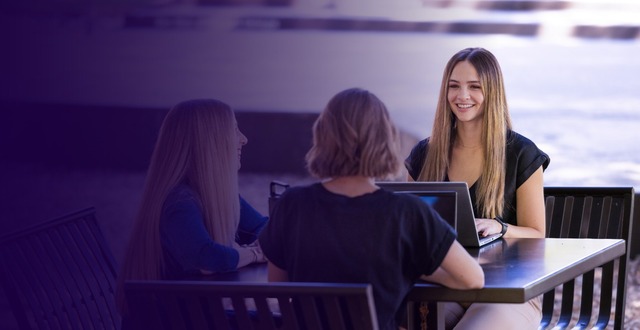 three women at a table with laptops