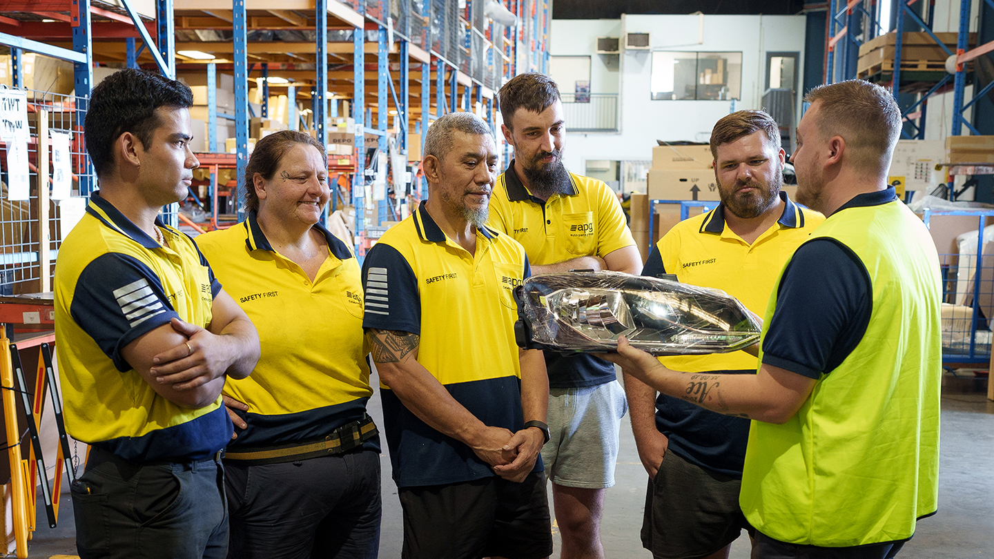 A large group of APG workers in high-visibility clothing posing in front of trucks, showcasing nationwide team presence and career variety.
