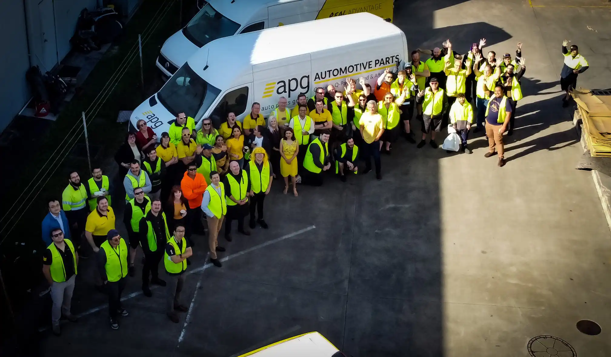 A large group of APG workers in high-visibility clothing posing in front of trucks, showcasing nationwide team presence and career variety.