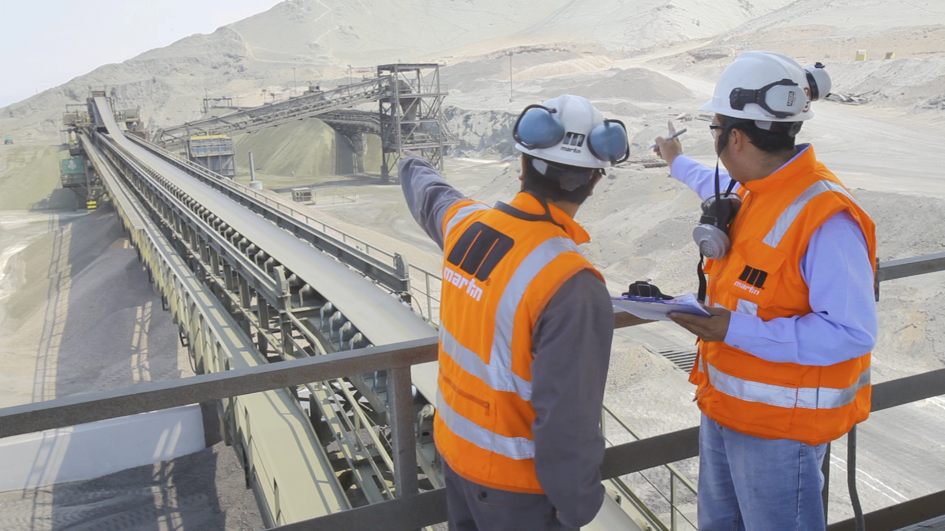 Workers in safety gear talking at an industrial site
