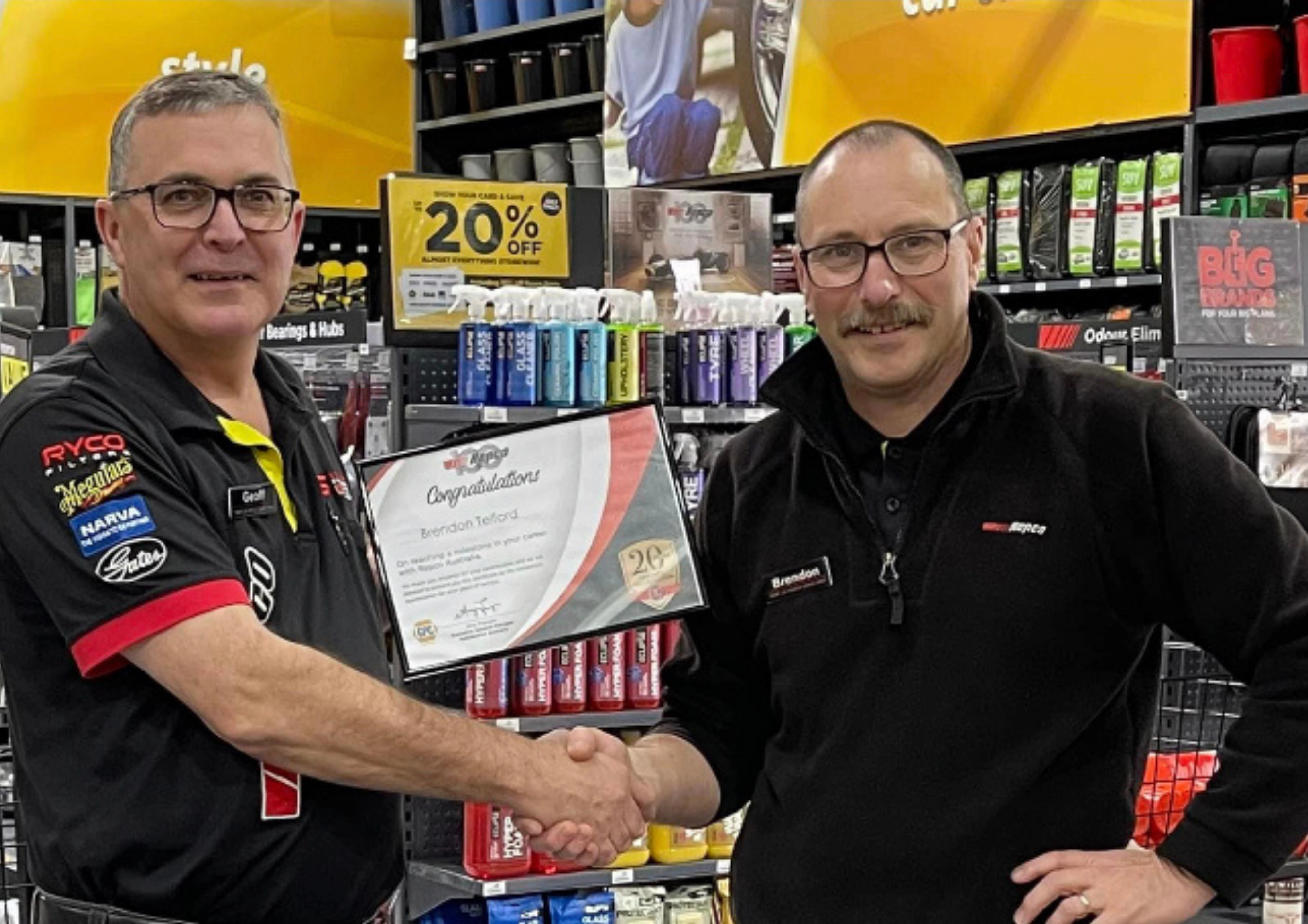 Two men smiling in a retail store aisle.