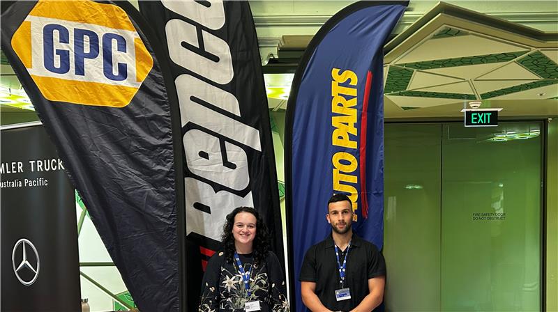 Team members at a company booth with branded banners.