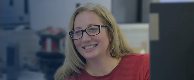 Woman sitting behind a computer monitor smiling