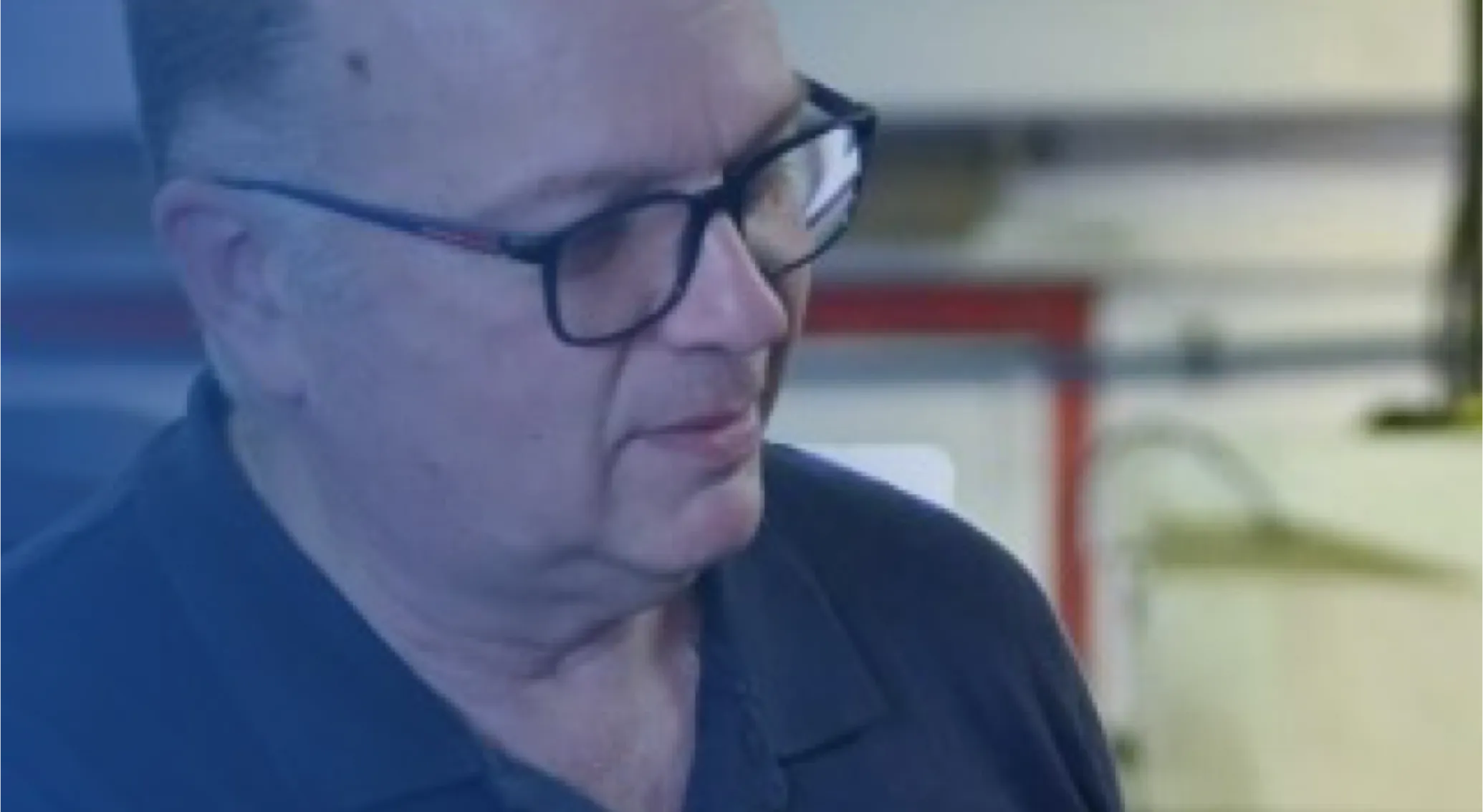 Man wearing glasses looking down in a workshop.