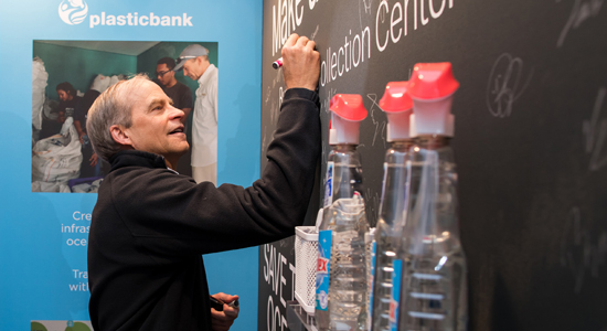 CEO Fisk Johnson signing commitment to reduce plastic waste on blackboard.