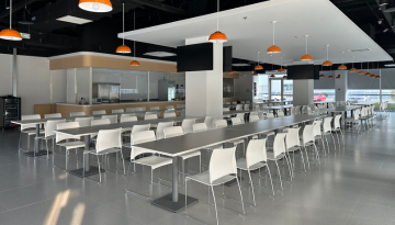 Bright, modern cafeteria area with long tables and chairs
