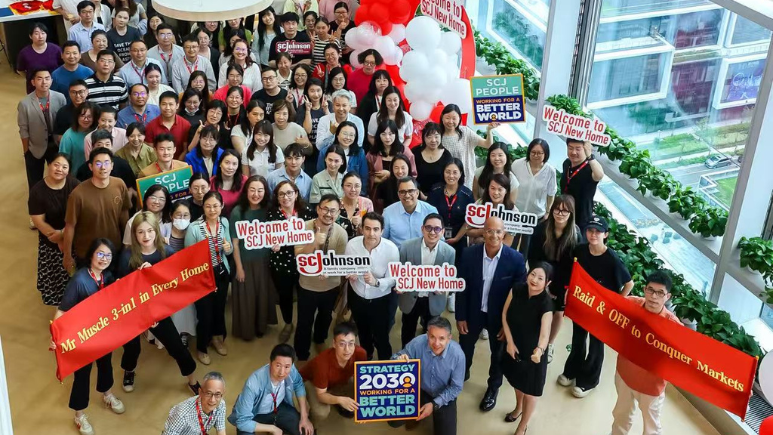 Group photo of SCJ China team members posing with welcome to new office signs