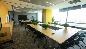 Conference room with long tables and chairs, sunlight coming through