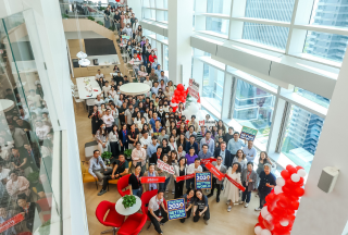 Group photo of team posed in lobby and on stairs with balloons and signs