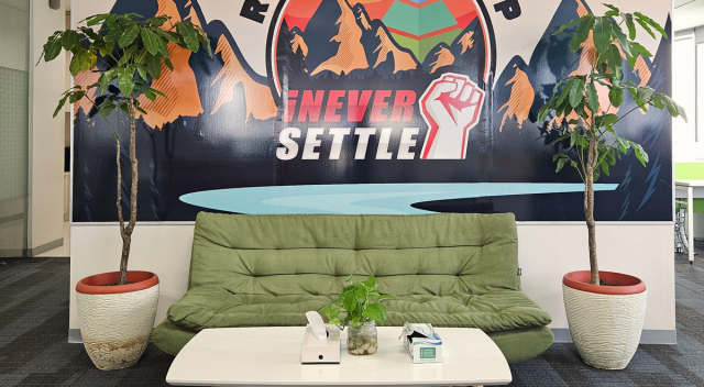 Seating area with couch and two trees, mural on wall behind couch