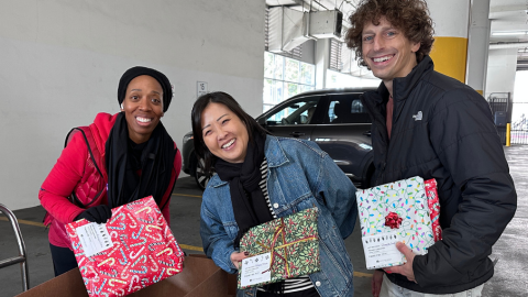 Three LSB team members holding gifts for an Adopt-a-Family program donation event