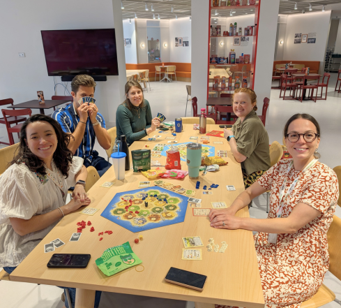 Five LSB UK team members playing a game at a table in the canteen