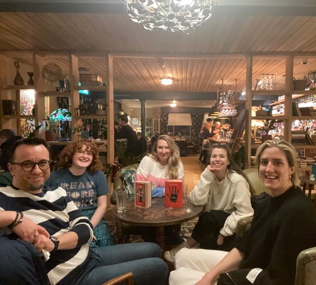 Five team members around a table discussing a book