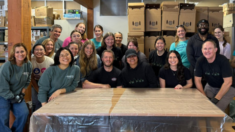 LSB team members in a group photo by boxes packed for a food bank volunteer event