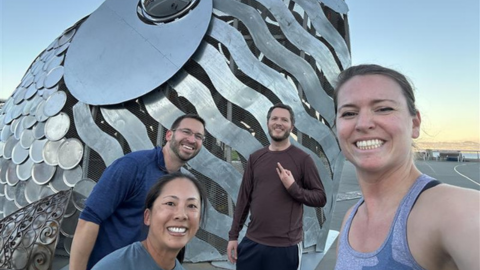Four LSB team members posing in front of a sculpture after a group run