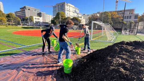Three LSB team members shoveling mulch at an outdoor cleanup event