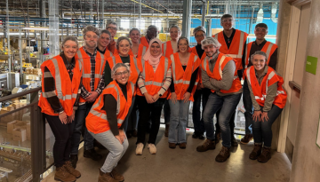 Group of RD&E team members pose together in safety gear at a manufacturing tour