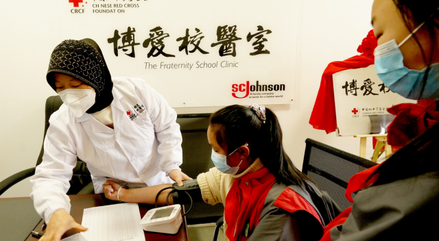 Photo of three people at clinic with medical provider giving care