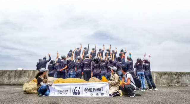 Group photo of SCJ China team members holding up WWF banner and pointing to sky