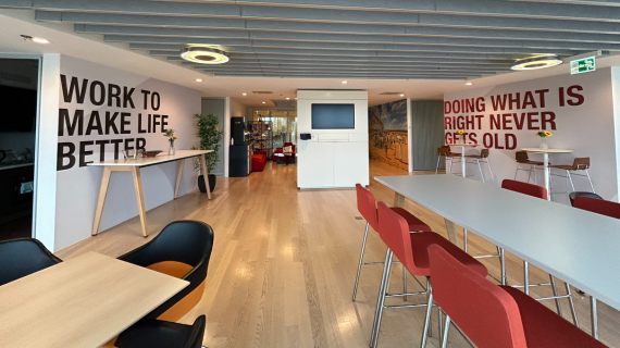 Interior of Switzerland office two tables with 'Work to Make Life Better" mural in background