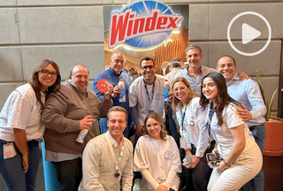 10 SCJ team members posing for a photo in front of Windex logo poster