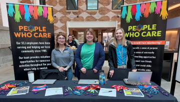 Three SCJ team members standing behind a table display at SCJ Learning Week