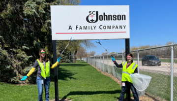 Two team members posing with SC Johnson sign at Earth Month clean up event