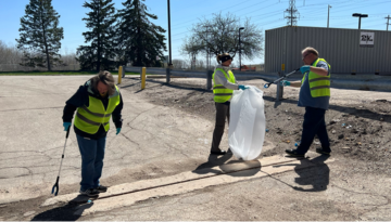 Three team members picking up litter at Earth Month volunteering event