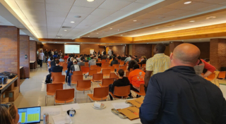 Team listening to presentation at front of meeting room