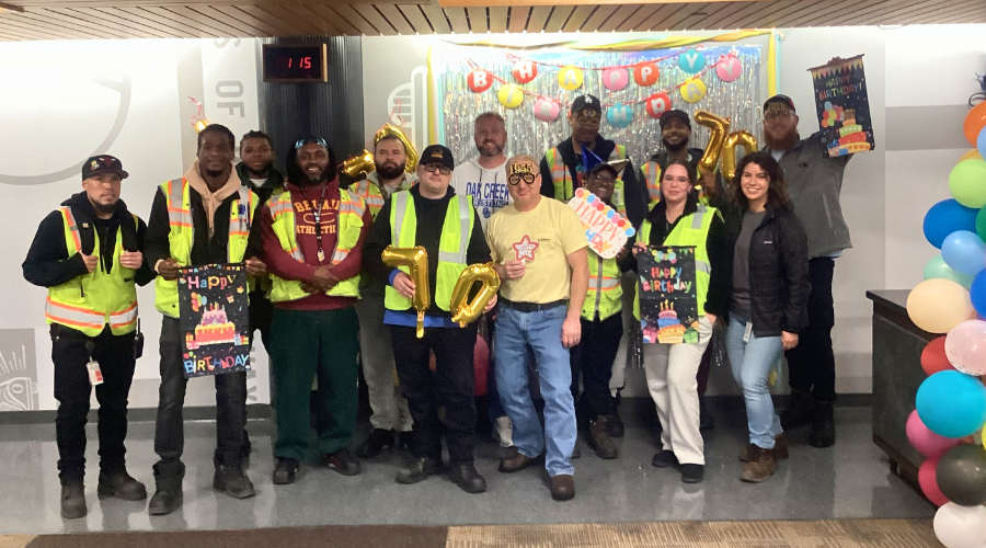 Team members pose for a group photo with birthday celebration props