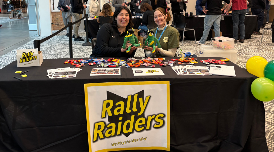Two Rally Raider volunteers posing at table with information