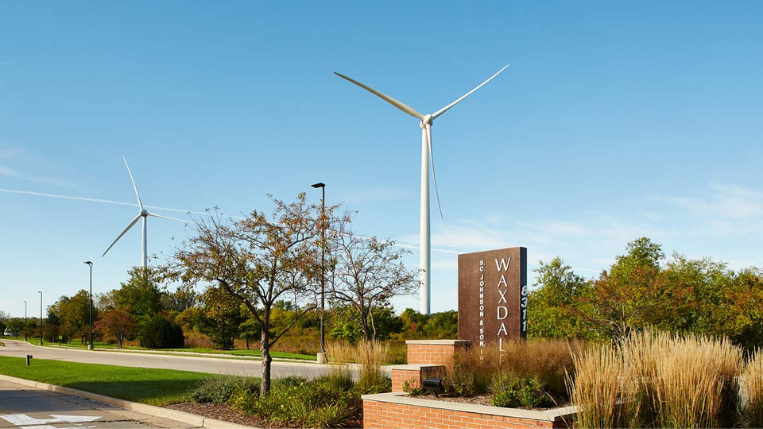 Front entrance to Waxdale facility property with two wind turbines in background