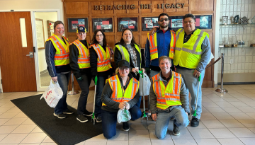 Group of SCJ Bay City team members wearing safety vests posing for a group photo at Earth Day clean up event