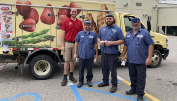 Four SCJ Bay City team members standing outside by a Food Truck at a team event