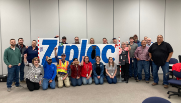 Group photo of SCJ Bay City team members posing by Ziploc sign