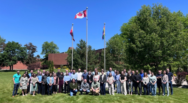 SCJ Canada Brantford office team photo - outdoors by flag poles
