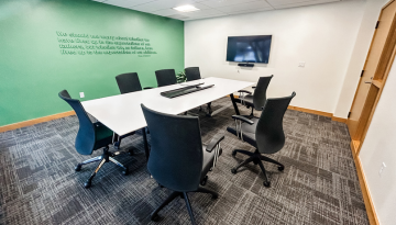 Meeting room with table, 8 chairs and a monitor on the wall
