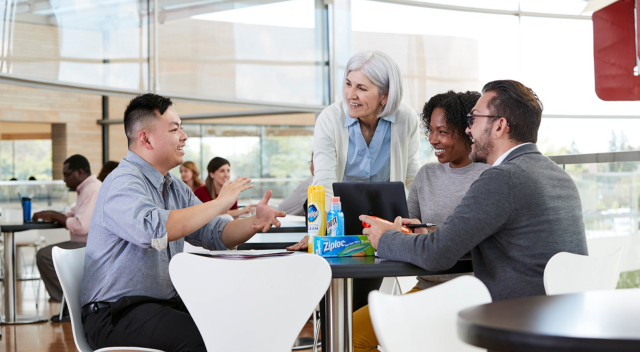 Group of four team members collaborating in cafeteria area