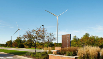 Entrance of Waxdale complex with sign and wind turbines in background