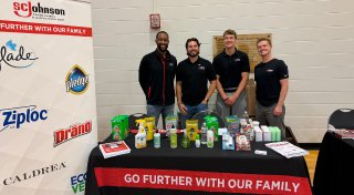 Four SCJ team members standing at a SCJ table at a recruiting event