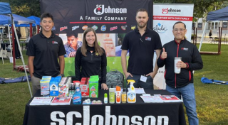 Four SCJ team members standing at table at a recruiting event